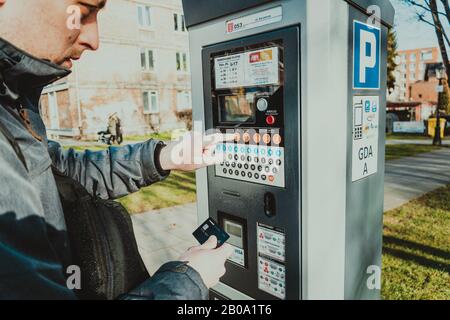 Man bezahlt für das Parken mit einer Kreditkarte mit NFS-Technologie. Einfache Zahlung. Zahlungsprozess im Automatenparkplatz. Parken im Stockfoto