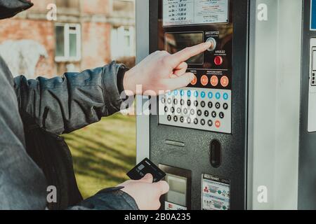 Man bezahlt für das Parken mit einer Kreditkarte mit NFS-Technologie. Einfache Zahlung. Zahlungsprozess im Automatenparkplatz. Parken im Stockfoto