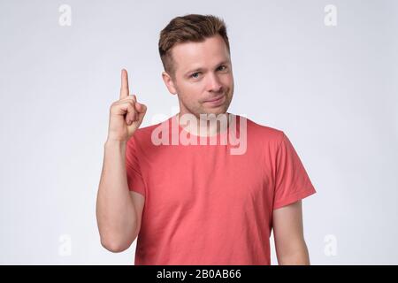 Zufriedener junger Mann, der Zeigefinger zeigt und Ratschläge oder Empfehlungen gibt Stockfoto