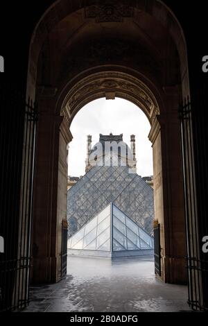 Die berühmten Pyramiden des Louvre, die durch einen Bogen in Paris gesehen werden. Stockfoto
