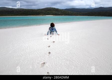 Mann mit lockigen Haaren, am Kieselstrand, Blick auf das Meer Stockfoto