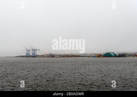 Weitwinkel Blick auf den Hafen von Saint John bei Flut. Das Wasser ist so hoch, dass es fast über den Docks liegt. Die Oberseite der Kräne ist durch Nebel verdeckt. Stockfoto