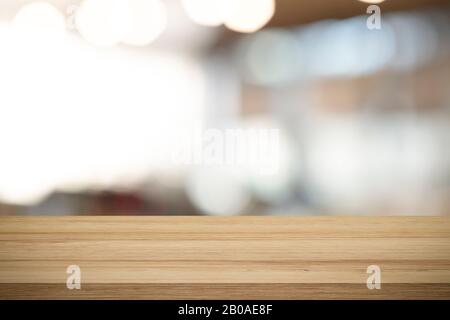 Leere Holz- Tabelle für das vorliegende Produkt auf Coffee shop oder Soft Drink Bar blur Hintergrund mit bokeh Bild. Stockfoto