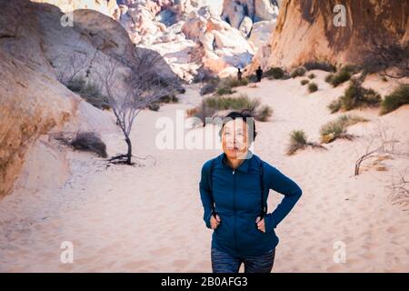 Ältere asiatische Frau beim Wandern in der Wüstenlandschaft Stockfoto