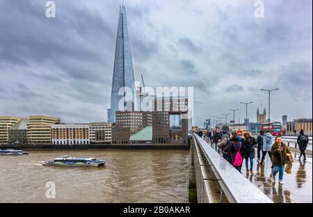 London Bridge über die Themse mit Blick auf die Schard- und South Bank Böschungsgebäude an einem nassen Wintertag mit dunklen stürmischen Wolken Stockfoto