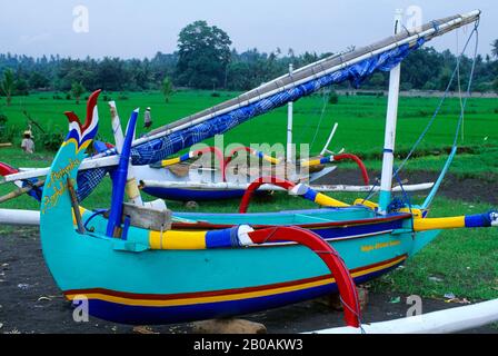 INDONESIEN, BALI, LEBIH, STRAND MIT FISCHERBOOTEN AUS HOLZ, REISFELDER IM HINTERGRUND Stockfoto