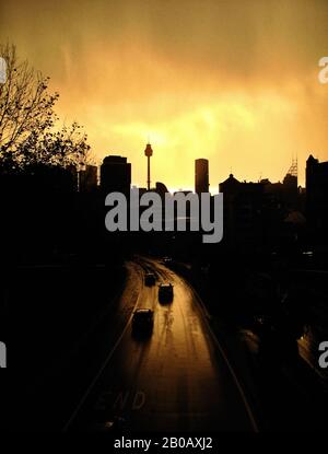 Dramatischer dunkler und vorausschauender, orangefarbener Himmel und Storm-Light Über Sydney vom William St Kings Cross mit einer Silhouette von Autos und der Skyline der Stadt Stockfoto