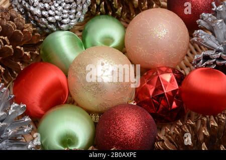 TIS THE SEASON: Weihnachtsschmuck und dekorative Tannenzapfen sitzen in einem Korb. Stockfoto