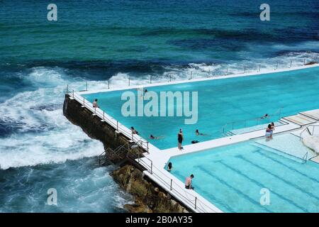 Schwimmer am berühmten Bondi Eisberge Ocean Pool, an einem sonnigen Tag mit klarem blauen Himmel und sonnigem Licht Stockfoto