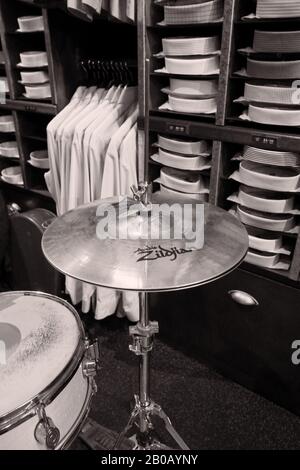 Snare und Cymbals, Musikinstrumente als Schwarz-weiß-Stillleben-Bilder in einem maßgeschneiderten Herrenmode-Geschäft mit Hemden in Regalen und hängen auf einem Regal Stockfoto