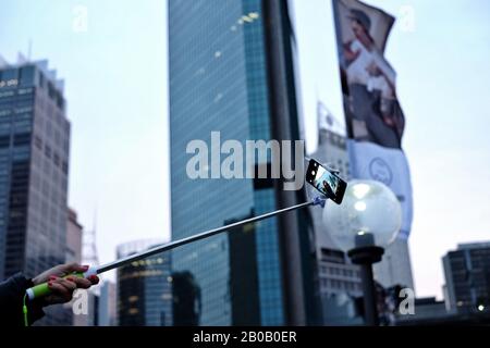 Ein Tourist macht ein sydney selfie, eine Hand hält einen selfie-stick und ein Smartphone, um ein Selbstporträt am Circular Quay mit hinterherliegenden Wolkenkratzern des CBD zu machen Stockfoto