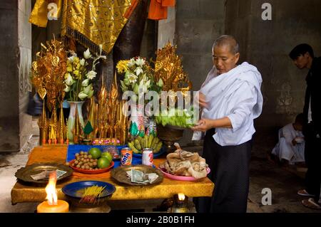 KAMBODSCHA, ANGKOR, ANGKOR WAT, GALERIE, STATUE DES HERRN VISHNU, HINDU-GOTTHEIT, DER KONSERVIERER, NONNE, DIE OPFERGABEN AN DER BASIS DER STATUE ARRANGIEREN Stockfoto