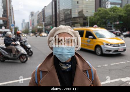 Taiwanerin auf der belebten Taipei Straße trägt Gesichtsmaske, um sich gegen die Kovid-19-Coronavirus-Epidemie zu schützen. Stockfoto