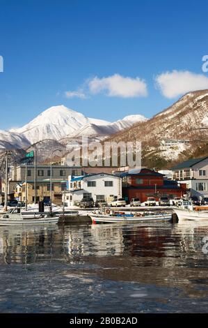 JAPAN, INSEL HOKKAIDO, RAUSU, FISCHEREIHAFEN MIT FISCHERBOOTEN, MT. RAUSU IM HINTERGRUND Stockfoto