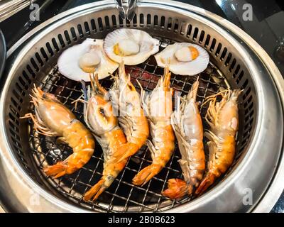 Gegrillte große Garnelen und Jakobsmuschel auf dem Brennofen. Fisch- und Meeresfrüchtegrill für Familienfeiern. Stockfoto