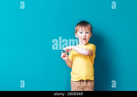 Kleiner Junge auf blauem Hintergrund, überrascht mit offenem Mund Stockfoto