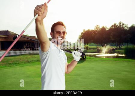 Ein gutaussehender männlicher Golfer feiert seinen Sieg. Stockfoto