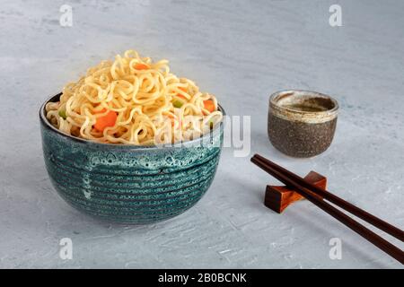 Nudeln in Sekt mit Karotten und Hengsten, mit Essstäbchen und Sake, Gemüsesoba-Schüssel mit Platz für Text Stockfoto