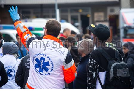 Ein Psychologe ruft jemanden außerhalb des Münchner Hauptbahnhofs an, während er im September 2015 neu eingetroffenen Zuwanderern aus Budapest assistiert Stockfoto