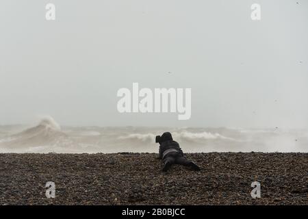 Ein Fotograf, der sich beim Sturm Ciara am 9. Februar 2020 vor der Küste von Sussex bei Newhaven fotografiert Stockfoto