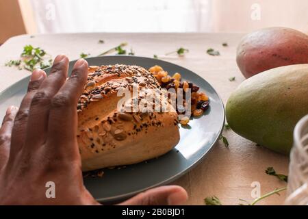 Gepflastertes Brot auf einem blauen Teller mit der Hand des afrikaners auf dem Bild, das menschliches Element hinzufügt Stockfoto