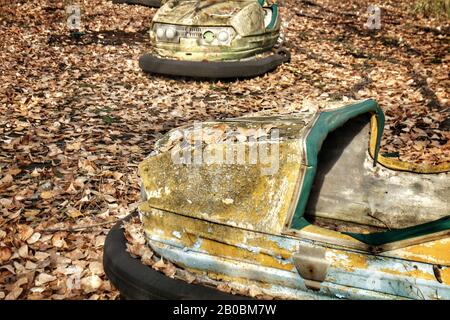 Die ikonischen gelben Stoßstangen des verlassenen Vergnügungsparks in der Sperrzone von Tschernobyl sind in Pripjat, Ukraine, mit Herbstblättern bedeckt. Stockfoto