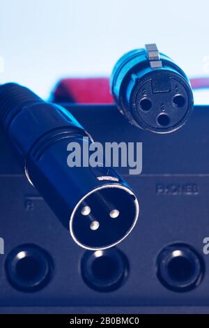 3-polige XLR-Stecker und -Buchse, die über dem Audiogerät mit Klinkenbuchsen hängen. Musik, Audio, Hi-Fi, Konnektivität und Tonwiedergabe. Stockfoto
