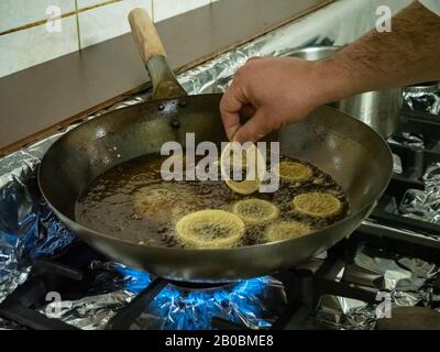 Ein Küchenchef Frites Indisch Pakora Zwiebel klingelt in heißem Öl über einem Gasherd in einer Restaurantküche Stockfoto