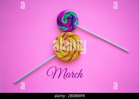Zwei helle Drall-Lollipops auf pinkfarbenem Hintergrund in Form von Nummer acht. Internationale Grußkarte für den Frauentag für den 8. März. Festlicher Hintergrund Wi Stockfoto