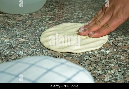 Ein Küchenchef würfelt und flacht naischen Brotteig auf einem Küchenarbeitdeck ab. Stockfoto