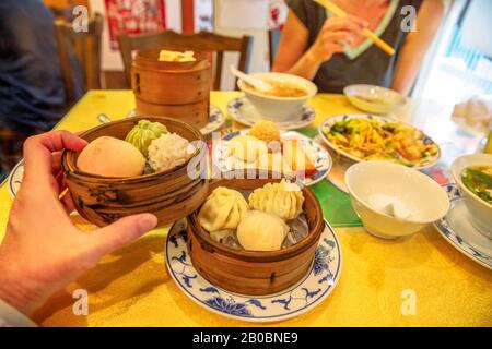 Tisch im chinesischen Restaurant in Yokohama Chinatown in Japan mit asiatischen Dampfklößen in einem Holzdampfer, gedämpften Brötchen, Ramen, Nudeln, Reis Stockfoto