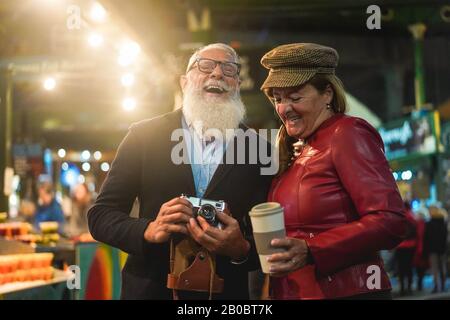 Glückliches älteres Paar, das zusammen Spaß hat, pH-Otos auf dem Straßennahrungsmarkt zu nehmen - Modefrau und Ehemann machen eine Stadtrundfahrt in London - Reisen und Freuden Stockfoto