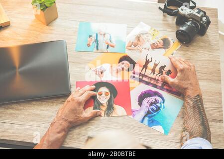 Tattoed Fotograf in seinem Kreativstudio, der Fotos auswählt - Hipper man bei der Arbeit Schnitt Bilder - Jobtrends, Mode und Technologiekonzept Stockfoto