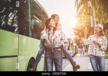 Fröhliche asiatische Freunde machen selfie-fotos mit Smartphones am Busbahnhof - Junge Studenten, die sich mit Technologietrends lustig machen - Freundschaft, Unive Stockfoto