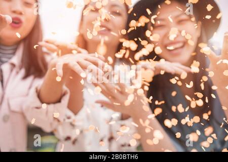 Verschwommene asiatische Freunde, die Spaß haben, Konfetti auf Party im Freien zu werfen - Junge Trendsleute genießen Festveranstaltung - Hangout, Freundschaft, Trends und Jugend Stockfoto