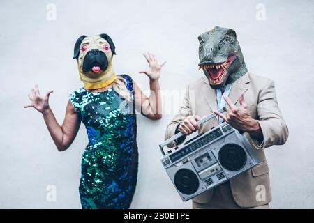 Verrücktes Seniorentanzpaar mit T-rex und Hühnchenmaske - Alte Trendsleute, die Spaß am Musikhören mit Boombox-Stereo haben - Absurd und f. Stockfoto