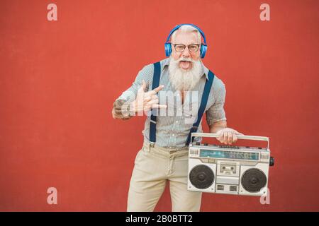 Hochrangiger verrückter Mann mit Boombox-Stereo, der Rockmusik spielt - Trendiger reifer Kerl, der Spaß beim Tanzen mit Oldtimer-Radio hat - Fröhliches älteres Lifestyle-Konzept - Stockfoto