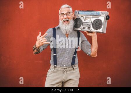 Hochrangiger verrückter Mann mit Boombox-Stereo, der Rockmusik spielt - Trendiger reifer Kerl, der Spaß beim Tanzen mit Oldtimer-Radio hat - Fröhliches älteres Lifestyle-Konzept - Stockfoto