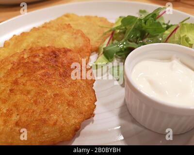 Kartoffelpuffer auf weißen Teller serviert mit Sauerrahm Stockfoto