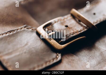 Echtes Leder in dunkelbrauner Farbe mit Messingverschluss. Handgefertigt. Lederhandwerk. Nahaufnahme Stockfoto