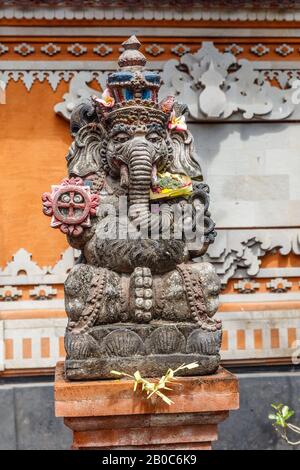Steinerne Hindu-Ganesha-Statue mit Blumen dekoriert. Bali, Indonesien. Vertikales Bild. Stockfoto