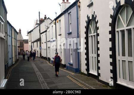 Woman Hiker, Der Durch die Irsha Street geht, eine Straße mit Pastellfarbenen Terraced Houses in Appletore am South West Coast Path, North Devon. Stockfoto