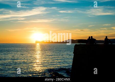Alghero, ITALIEN - 17. SEPTEMBER 2017: Menschen, die den Sonnenuntergang am Mittelmeer an den Wänden der Altstadt von Alghero, Sardinien, Italien, beobachten Stockfoto