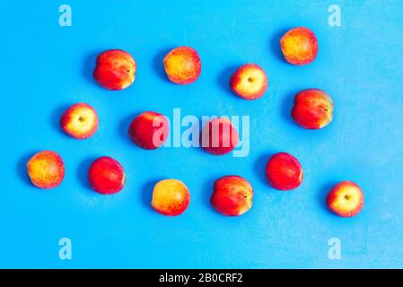 Flache Komposition mit reifen Pfirsichen auf blauem Grund. Frisches Obst mit Vitaminen. Gesunde Ernährung Stockfoto