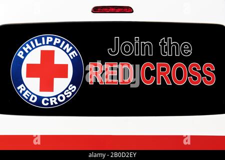 Iloilo City, Philippinen: Nahaufnahme eines Schildes und Emblems Des Roten Kreuzes, das an einer getönten Heckscheibe eines Rettungswagens befestigt ist Stockfoto