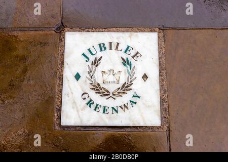 Namenskachel für den Jubilee Greenway auf dem Queen's Walk am Südufer des Themse-Embankment, London an einem nassen Tag Stockfoto