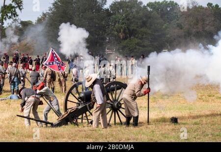 Brooksville, FL - 19. Januar 2020: Bürgerkriegsreenactors feuern bei einer Veranstaltung in Brooksville, FL, einen großen Kanon mit einer konfföderierten Flagge im Hintergrund ab Stockfoto