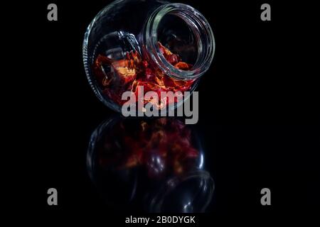 Rote heiße Chili Peppers in einem Glasbecher über schwarzem Hintergrund Stockfoto