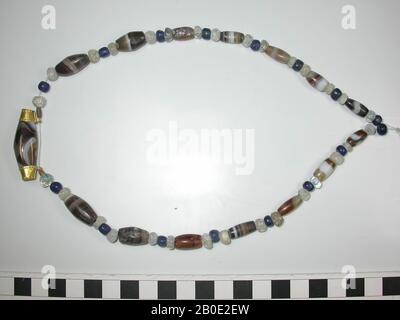 Halskette von rund bis abgeflacht rund und auch lange, zylindrische Perlen aus Stein, Glas und Gold. 16 kleine runde Kügelchen aus blauem Glas, 30 kleine runde bis flache Kügelchen aus farblosem bis milchigem weißem Glas oder Stein, 14 nach unten zylindrische Kügelchen aus braunem und weißem Sardonyx wie geschichtete Steine, 2 kleine längliche Perlen aus Gold und schließlich in der Mitte unten eine sehr lange zylindrische Perle aus braun-weiß sardonyx geschichteten Stein, zwischen zwei goldenen Ringen mit Perlen und Rosetten und Augen. Alle Kügelchen sind nahezu perfekt erhalten. Gut an der modernen Schnur aneinandergereiht. Gesamt: 63 Perlen, Schmuck, Metall, Gold Stockfoto