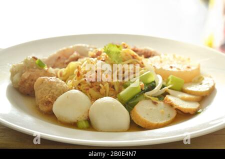 Getrocknete pikante chinesische Eiernudeln, die Fisch und Garnelenkugel mit geschliffenem gekochtem Schweinefleisch auf dem Teller überfüllen Stockfoto